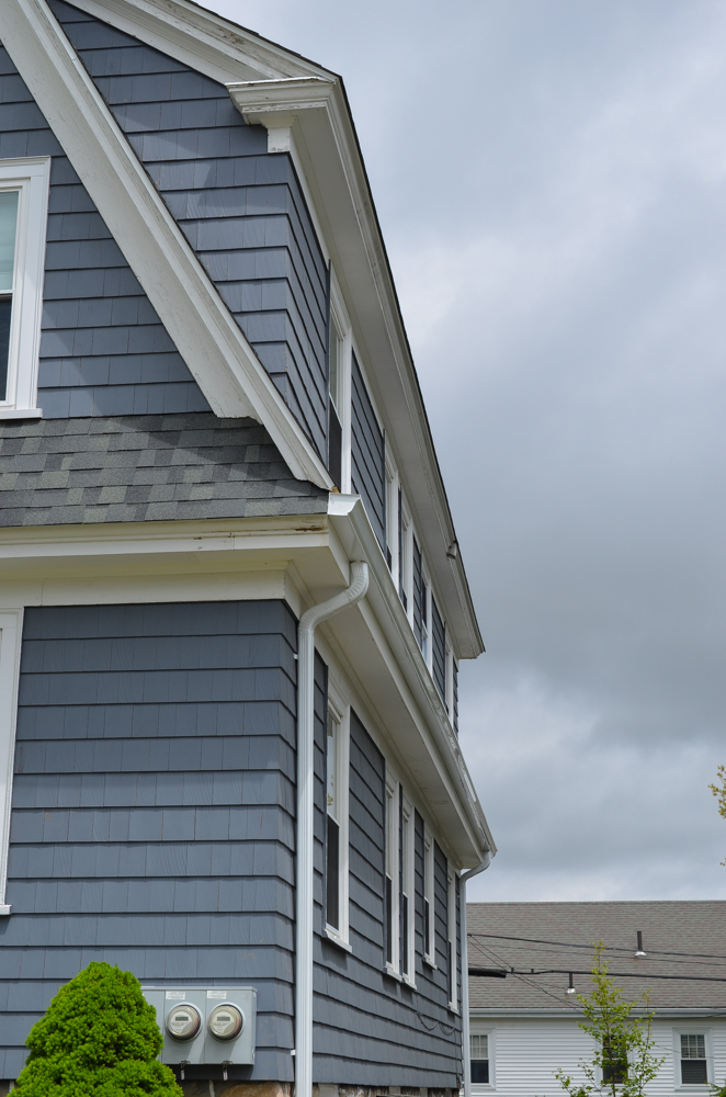  A home with blue siding and new gutters and downspouts. 